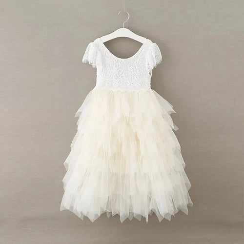 A white toddler girl's party dress with a lace bodice and layered tulle skirt, hanging on a white plastic hanger against a neutral gray background.